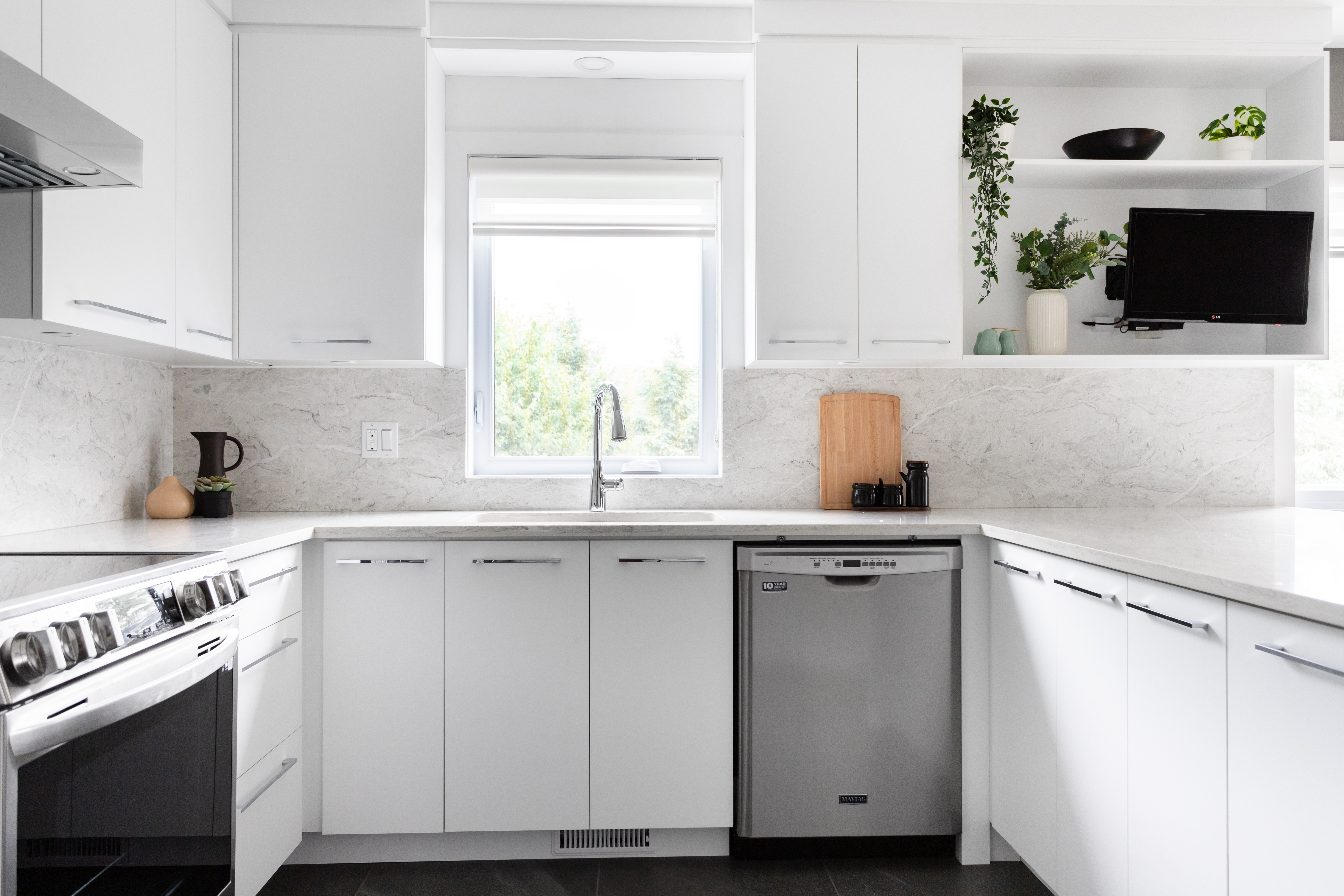 Magnifique cuisine moderne blanche polymère avec des comptoirs et dosseret en quartz.