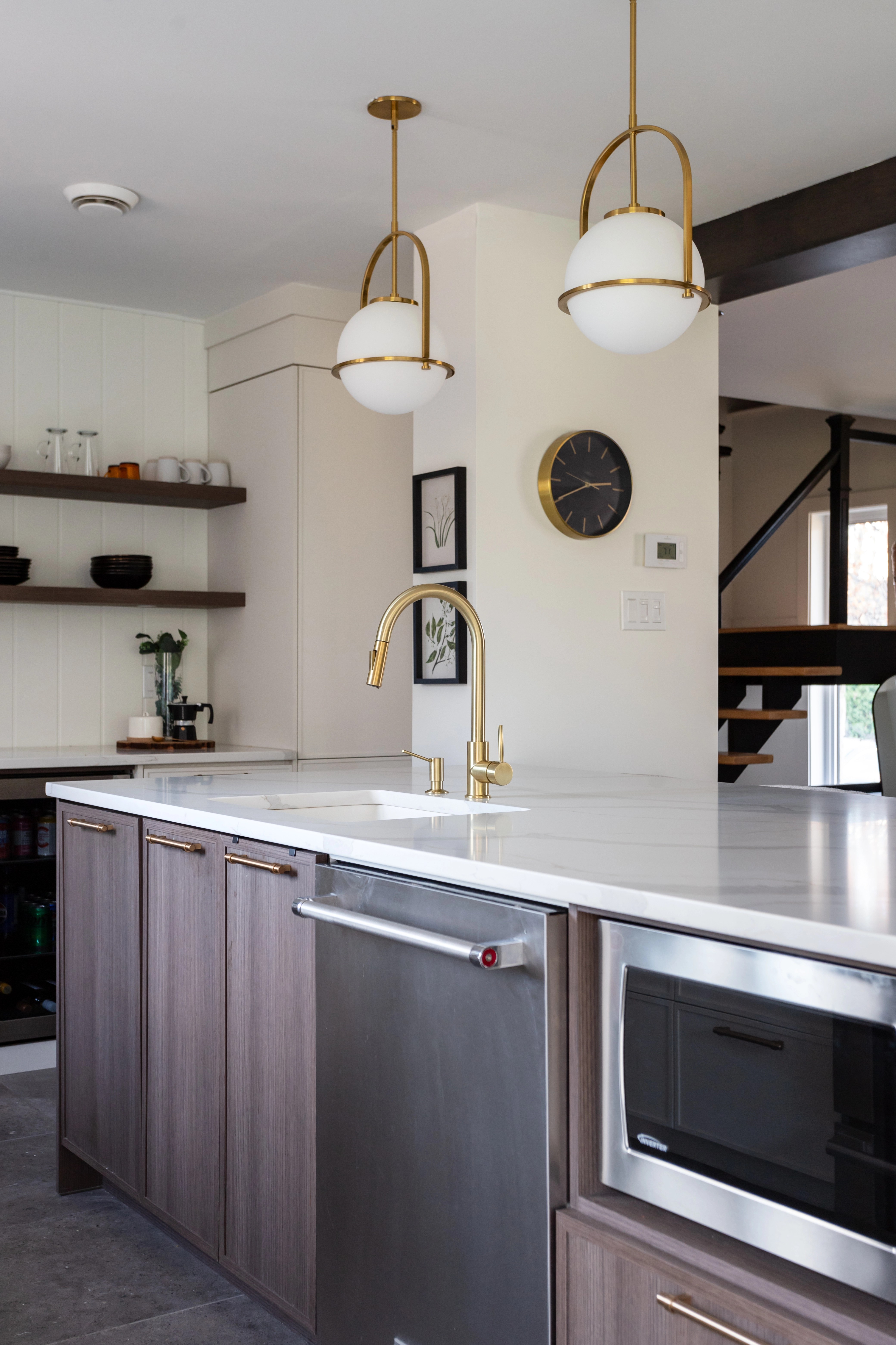 Cuisine ouverte avec îlot central et luminaires dorés. Design intemporel et chaleureux à Bécancour, Trois-Rivières, Québec, par l'équipe de designer d'intérieur d'Élévation Studio Design.