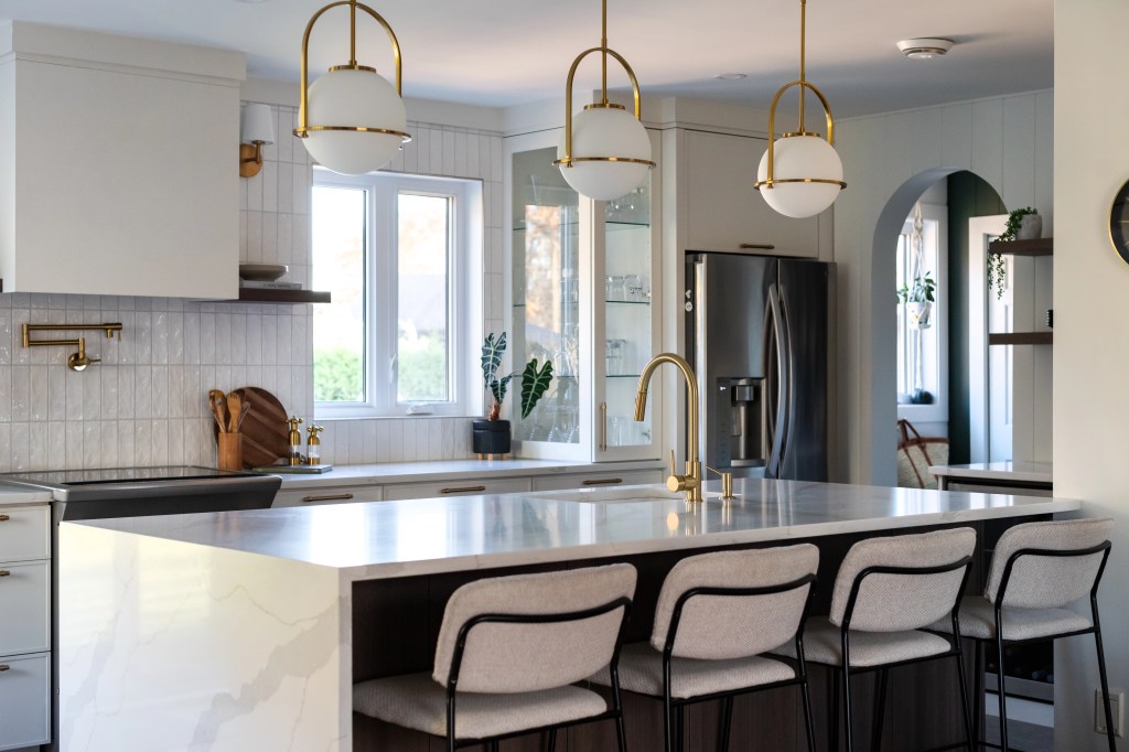 Cuisine ouverte avec îlot central et luminaires dorés. Design intemporel et chaleureux à Bécancour, Trois-Rivières, Québec, par designer d'intérieur d'Élévation Studio Design.