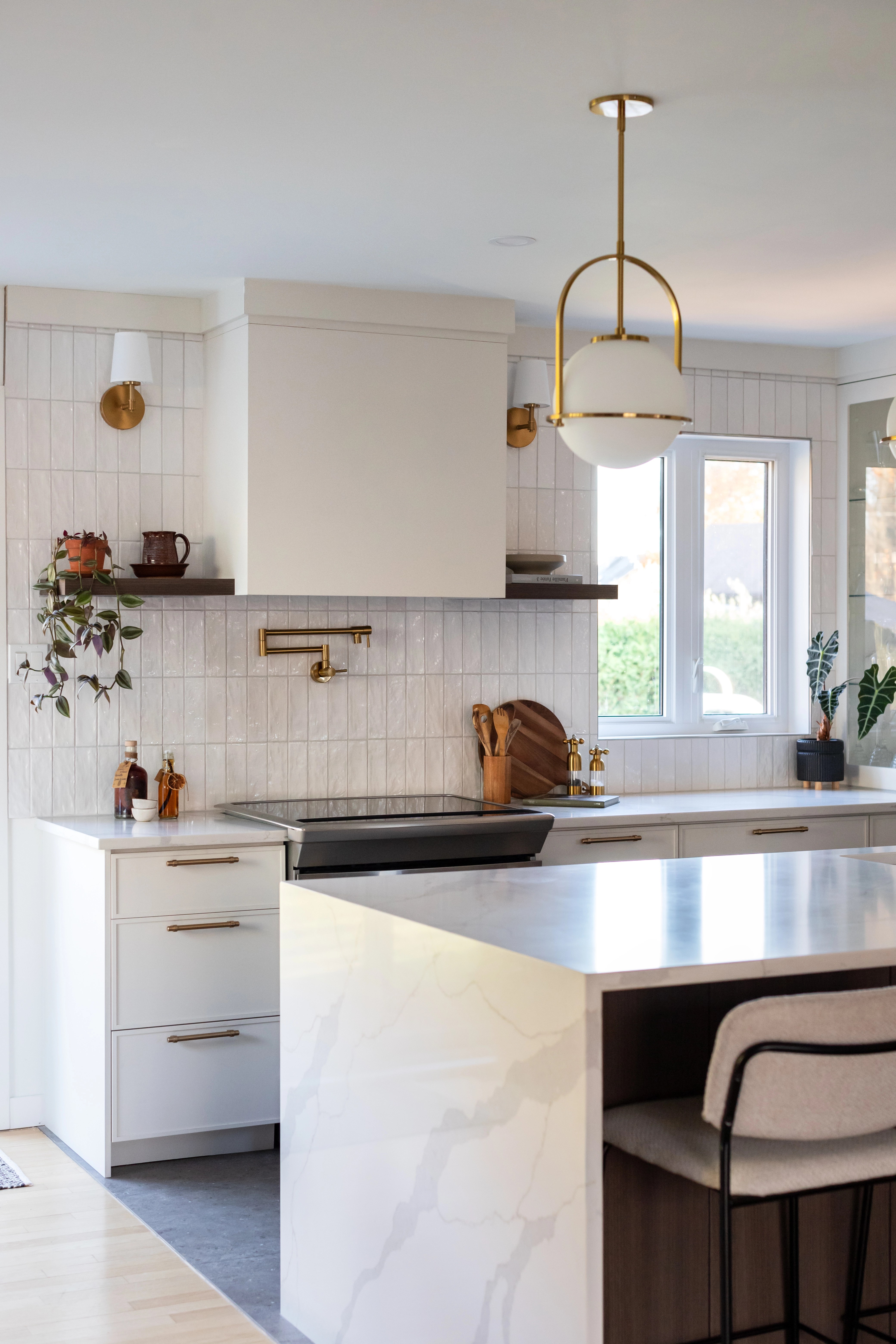 Cuisine ouverte avec îlot central et luminaires dorés. Design intemporel et chaleureux à Bécancour, Trois-Rivières, Québec, par l'équipe de designer d'intérieur d'Élévation Studio Design.