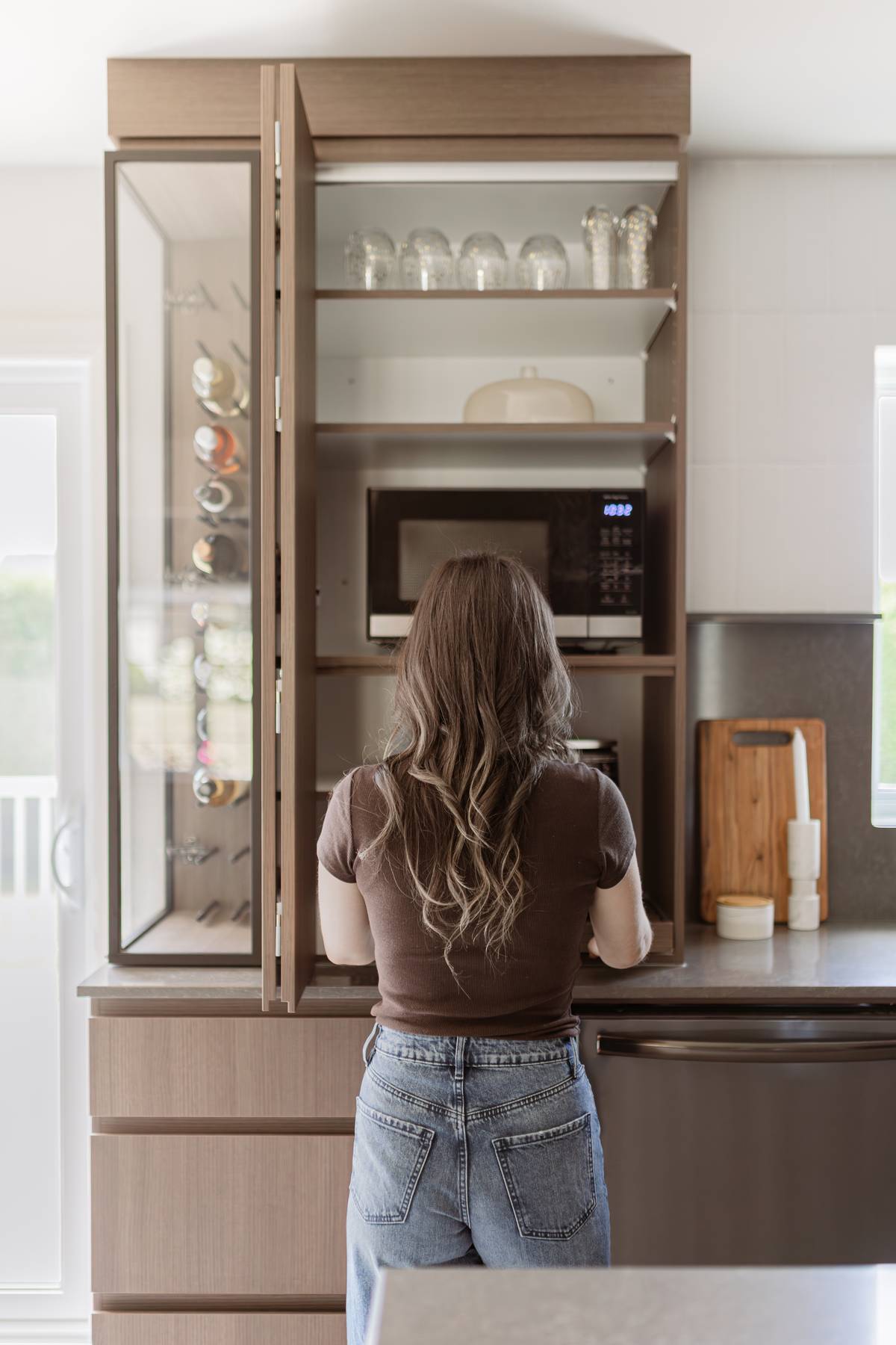 Rénovation de cuisine moderne en bois et noir mat avec îlot central et comptoir de quartz gris. Style chaleureux et contemporain à Acton Vale, Québec, signé Élévation Studio Design.
