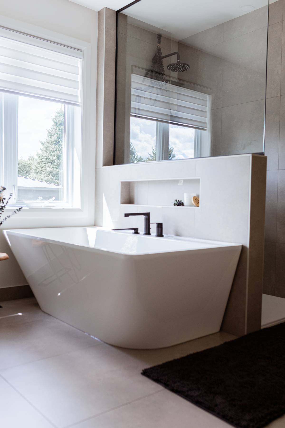 Salle de bain rénovée avec bain autoportant et douche moderne, design harmonieux et fonctionnel à Acton Vale, Québec, par Élévation Studio Design.
