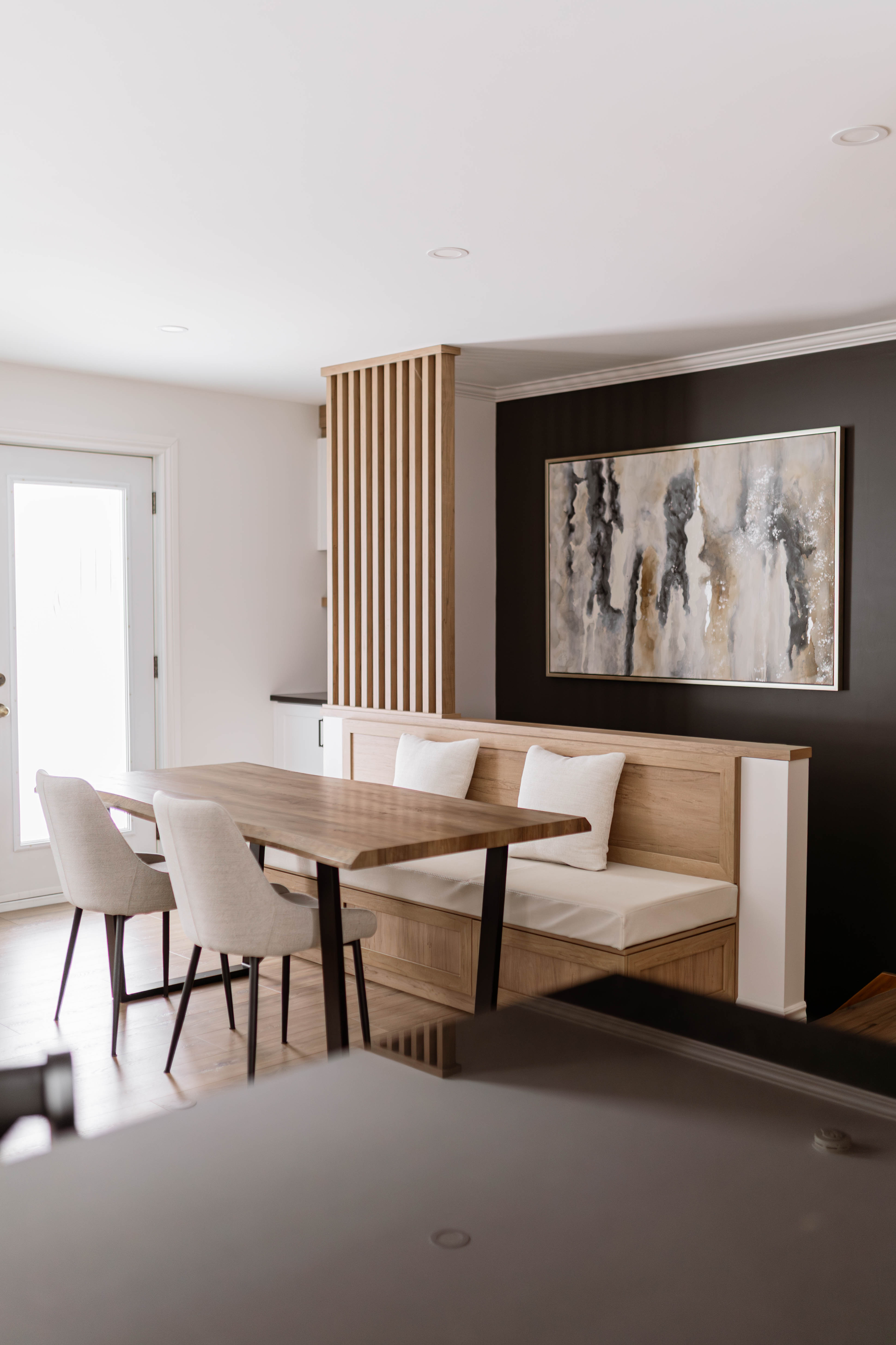 Banquette sur mesure de la salle à manger avec du rangement intégrés. Banquette effet bois. Banquette qui sert de garde-corps pour les escaliers. Garde-corps d’escalier avec lattes verticales en bois – design contemporain. Rénovation résidentiel à Saint-Ferdinand par Élévation Studio Design à Thetford Mines
