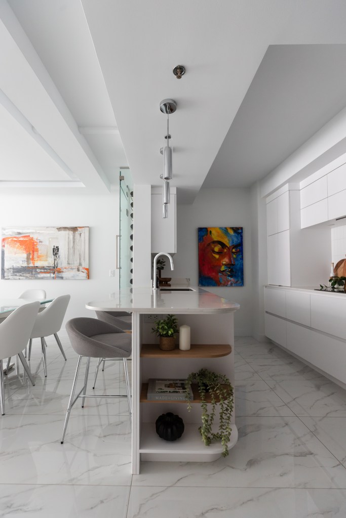 Projet de rénovation majeure de l'aire ouverte d'un condo à Québec - Cuisine sur mesure, blanche avec comptoir de quartz blanc, plancher porcelaine effet marbre - style contemporain moderne - péninsule avec l'extrémité courbé - péninsule avec cellier intégré - designer d'intérieur et cuisiniste, Élévation Studio Design à Thetford Mines