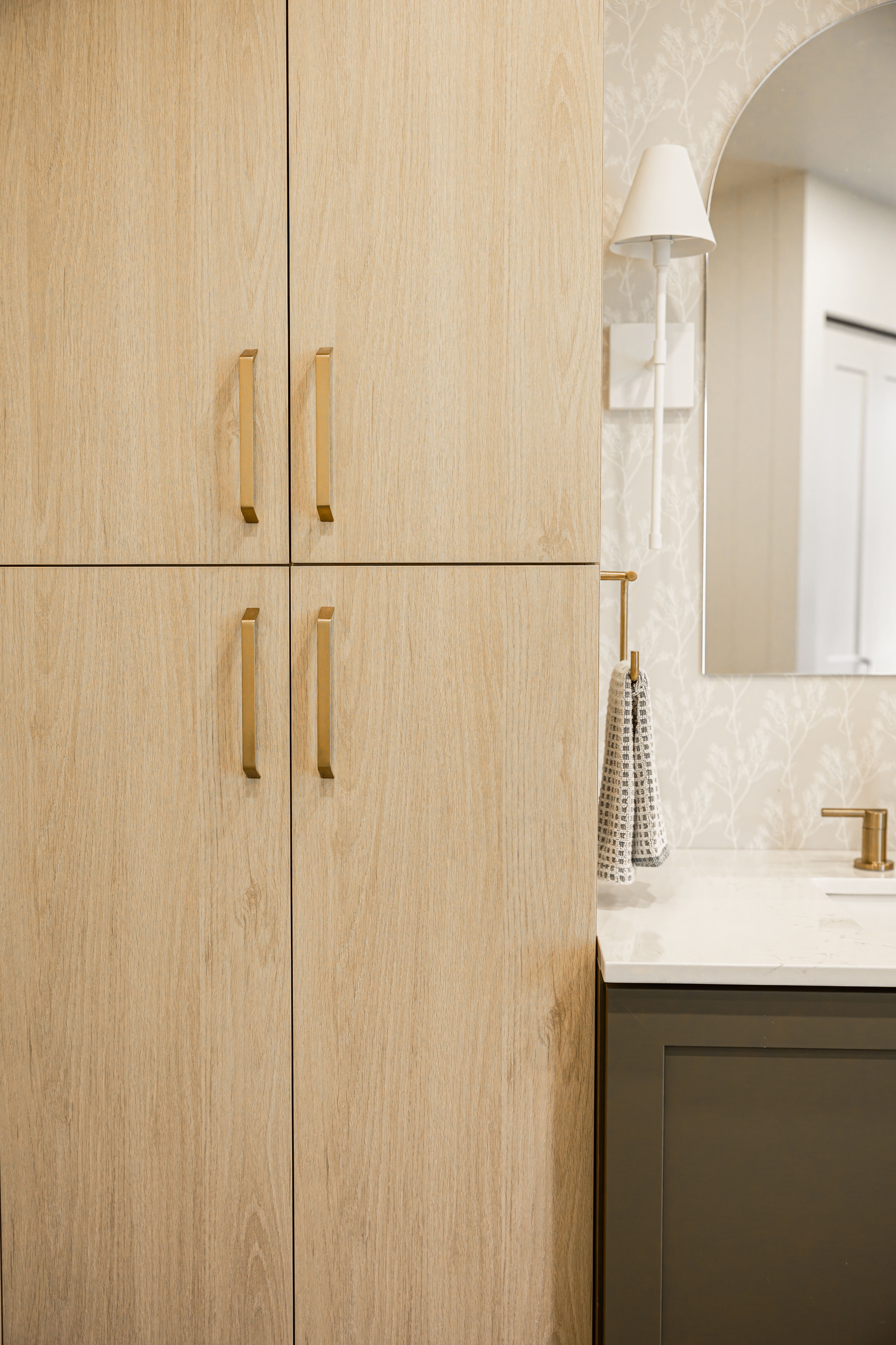 Grande armoire de rangement effet bois pâle à côté d'une vanité vert sauge et d'un miroir en arche | rangements de salle de bain | designer d'intérieur, Élévation Studio Design à Thetford Mines