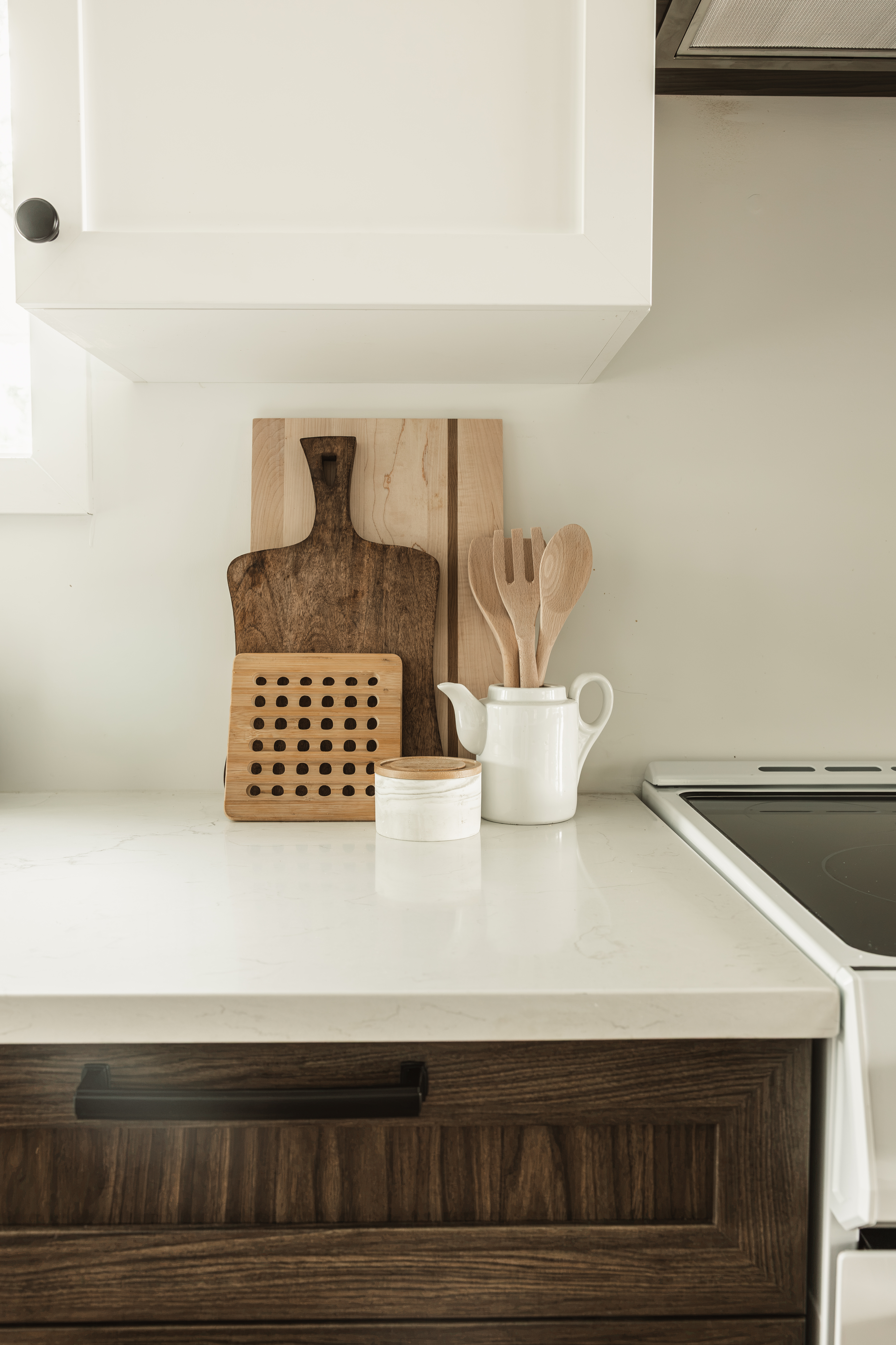 Détail d'un comptoir de cuisine en quartz blanc avec planches à découper et armoires basses en bois foncé