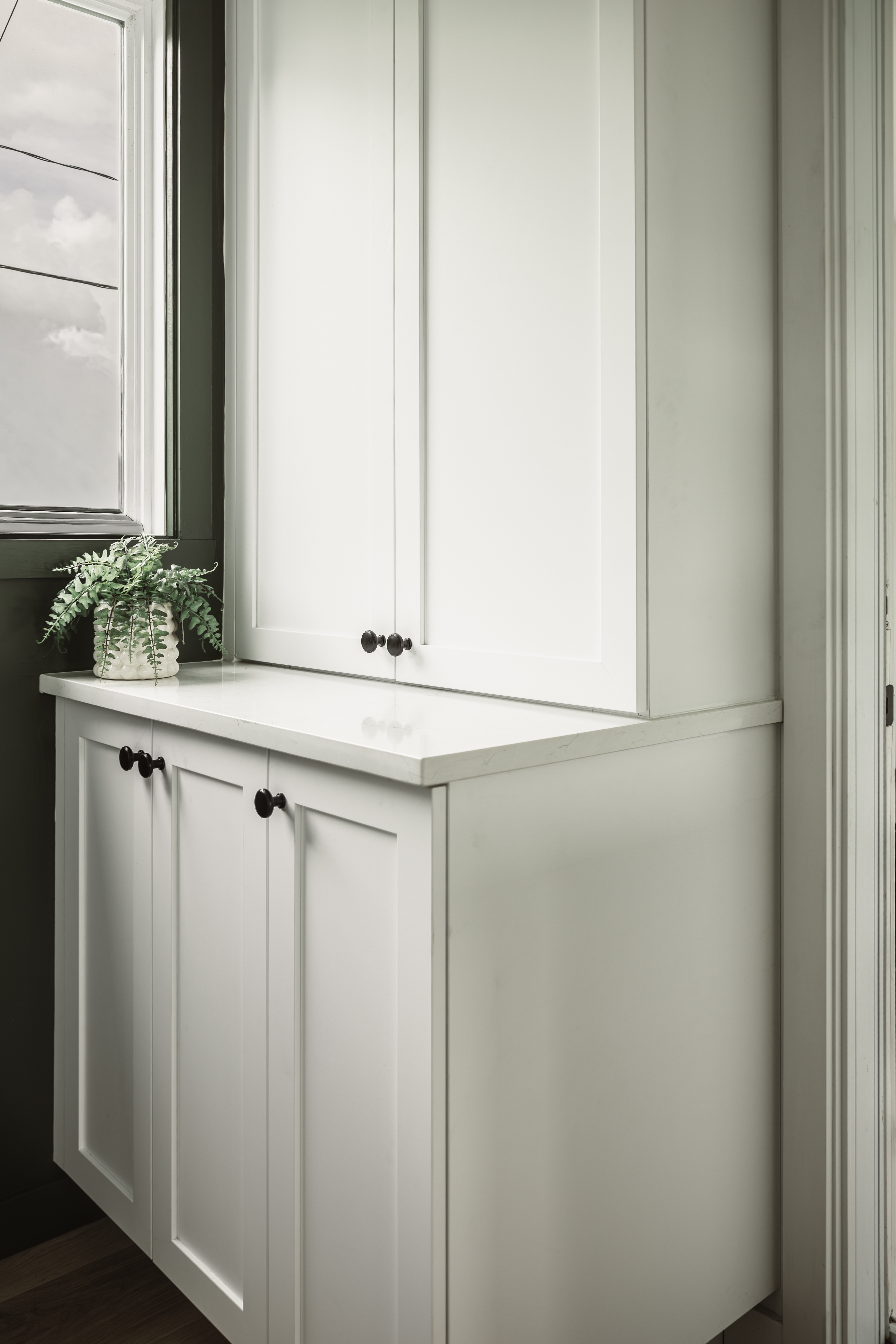 Armoires de rangement, qui cache le tableau électrique, blanches de style shaker avec plan de travail intégré dans un chalet rénové à Disraeli.