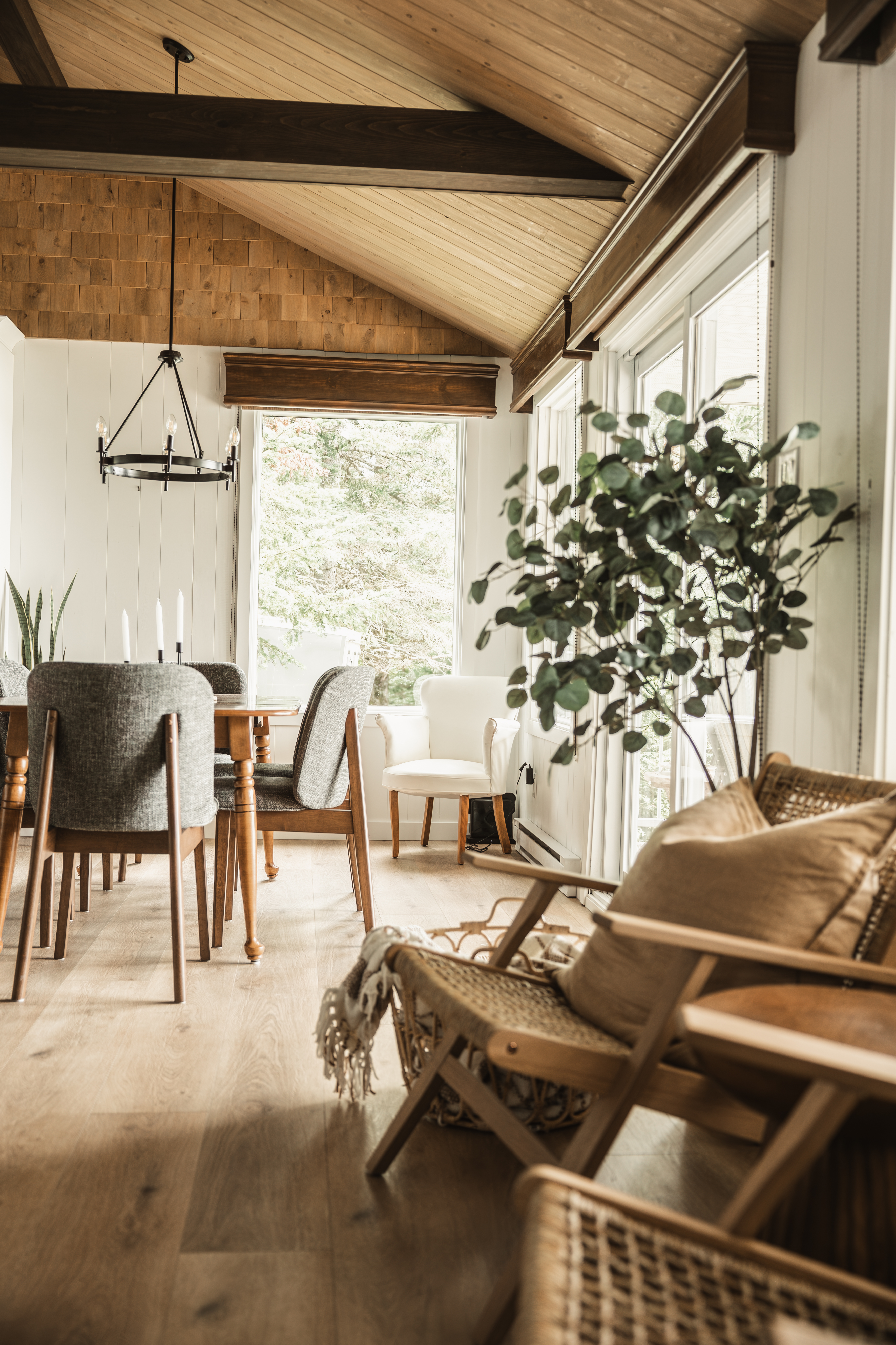 Salon et salle à manger à aire ouverte avec fauteuils en cannage et plafond cathédrale en bois. Chalet de style farmhouse, paisible et invitant à Disraeli.