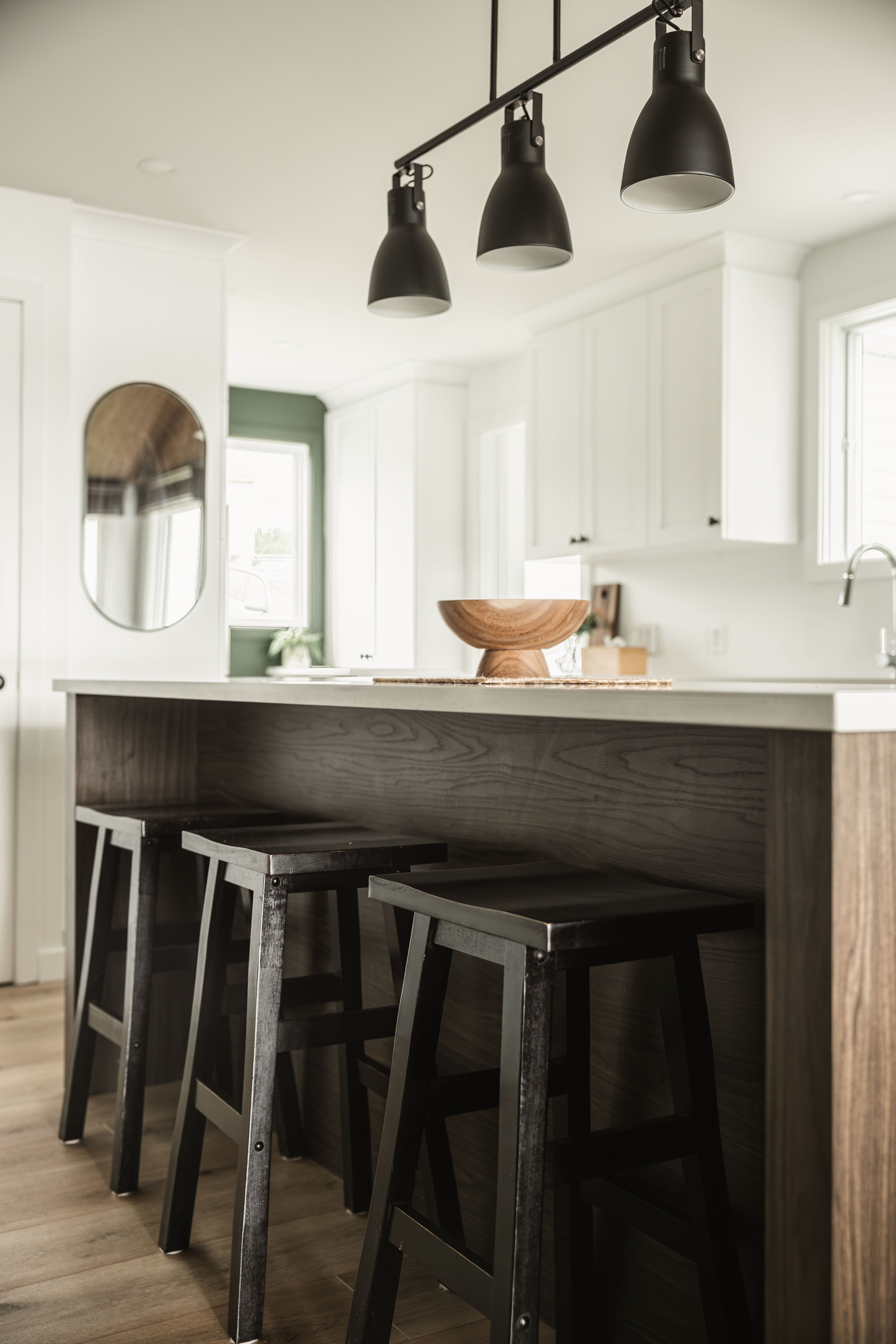 Vue rapprochée de l'îlot de cuisine avec comptoir de quartz blanc, tabourets noirs et luminaires suspendus. Le design intérieur se trouve dans les détails de vos intérieurs.