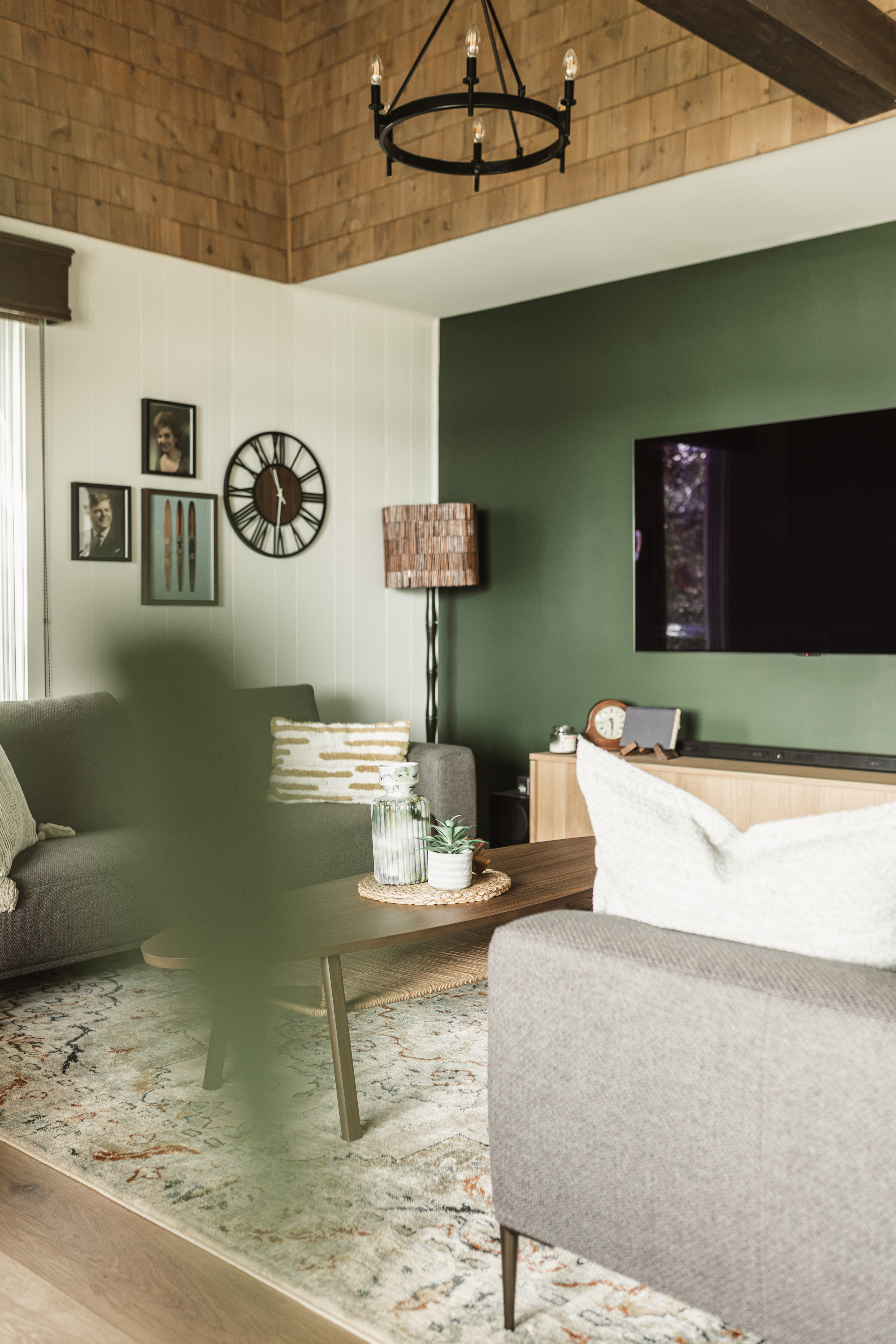 Salon du chalet familial avec mur vert forêt, mur de cadres, lustre noir et plafond cathédrale en bois | décoration et staging de salon | designer d'intérieur, Élévation Studio Design à Thetford Mines