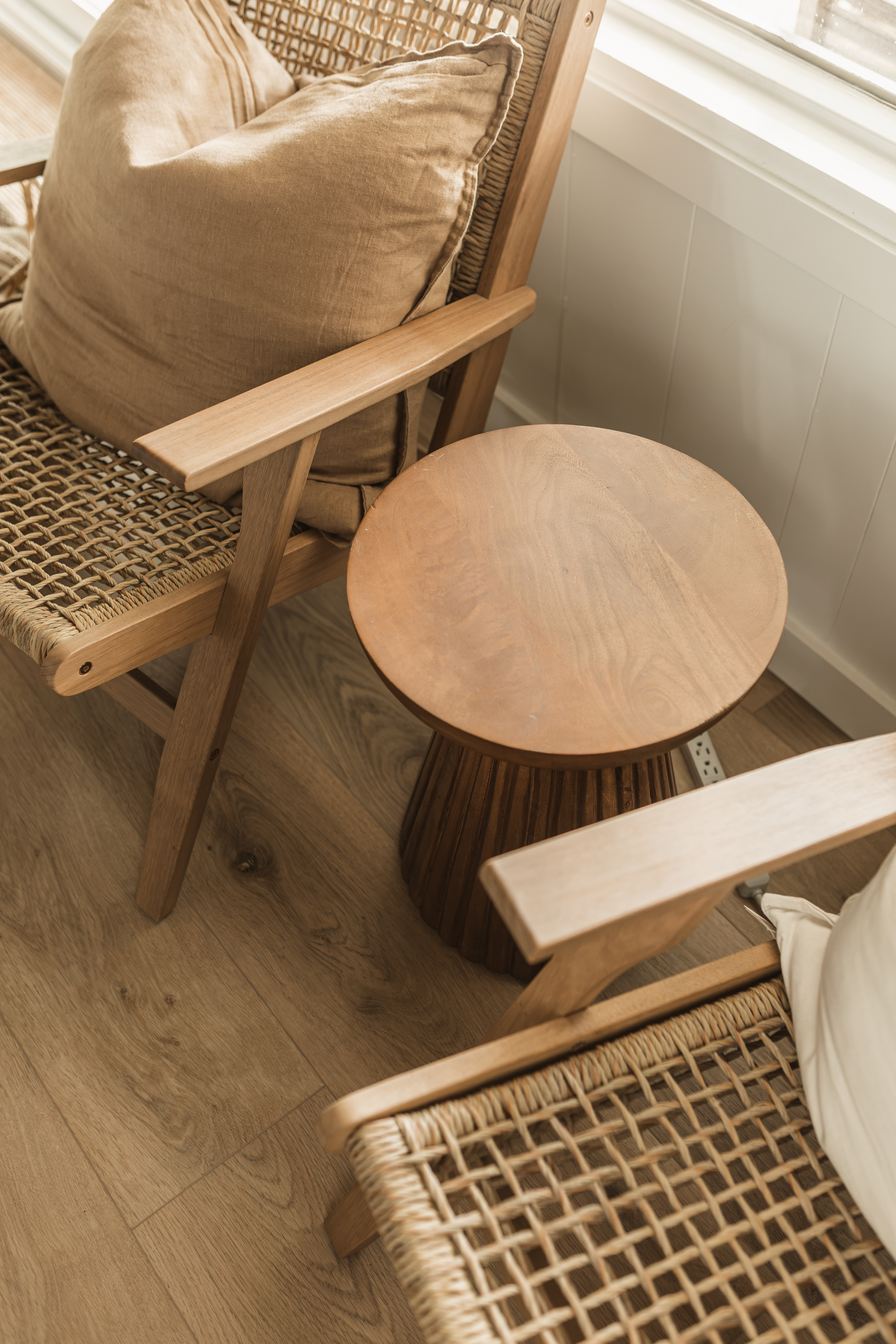 Détail des fauteuils en bois et cannage avec table d'appoint ronde en bois et coussin beige. Service de staging de décoration en Chaudière-Appalaches