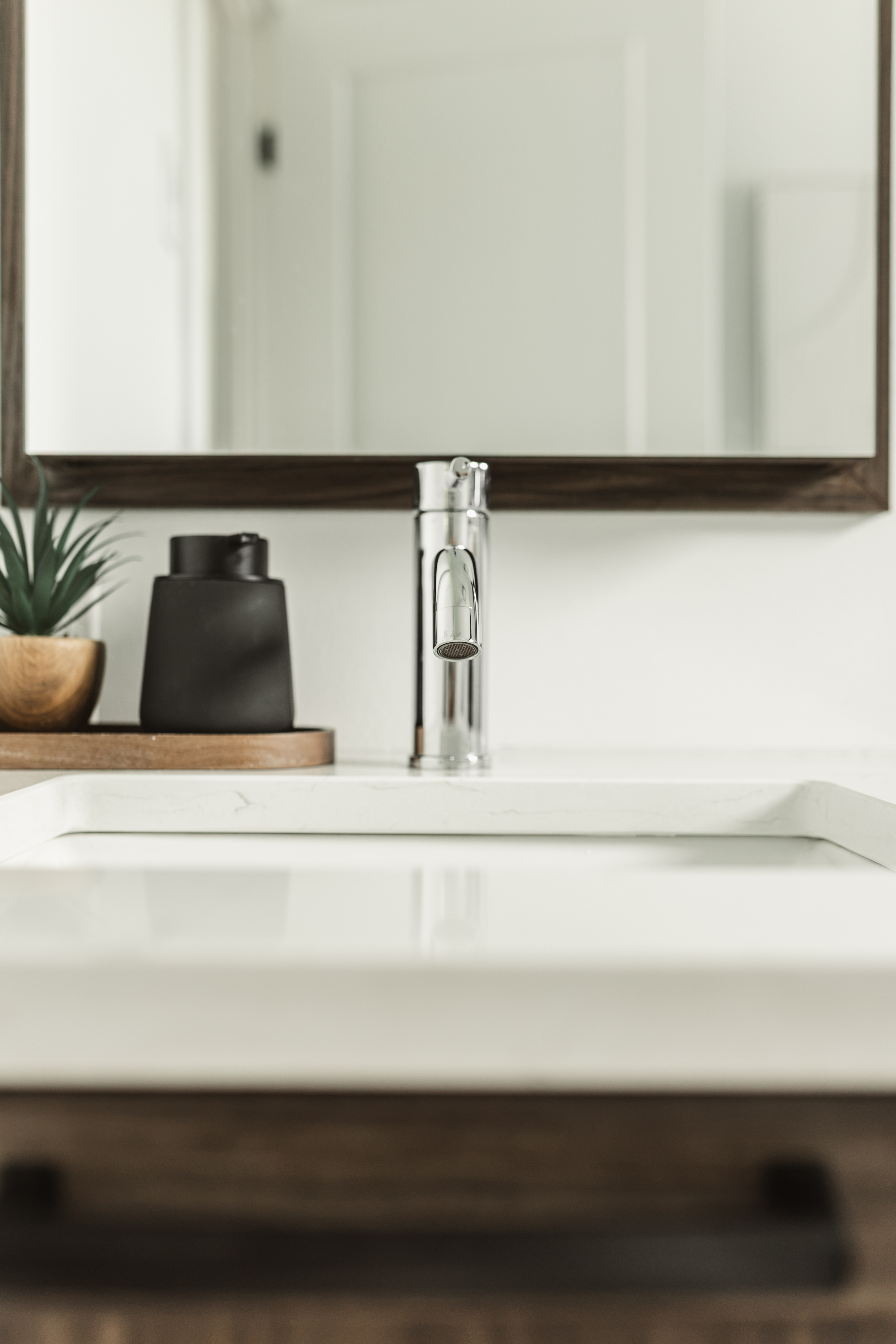 Détail d'un lavabo avec robinet et comptoir de quartz blanc avec armoire pharmacie et miroir sur mesure par l'ébénisterie.