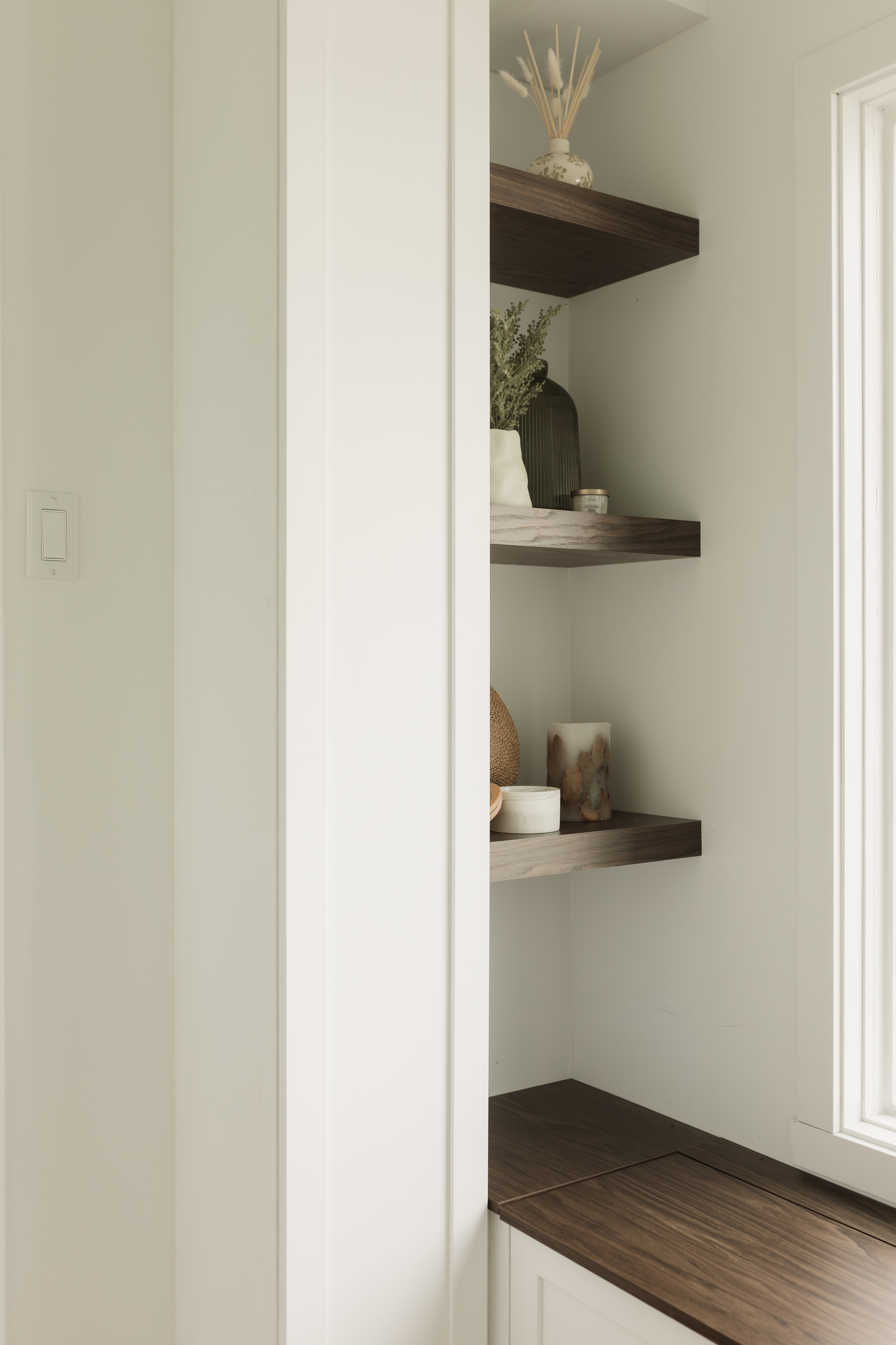 Rangement dans l'entrée fait sur mesure. Armoire pour y intégrer le compteur électrique avec des tablettes décoratives effet bois. Banquette sur mesure sous la fenêtre avec du rangement intégré, dessiné par Kelly-Anne, designer d'intérieur à Thetford Mines