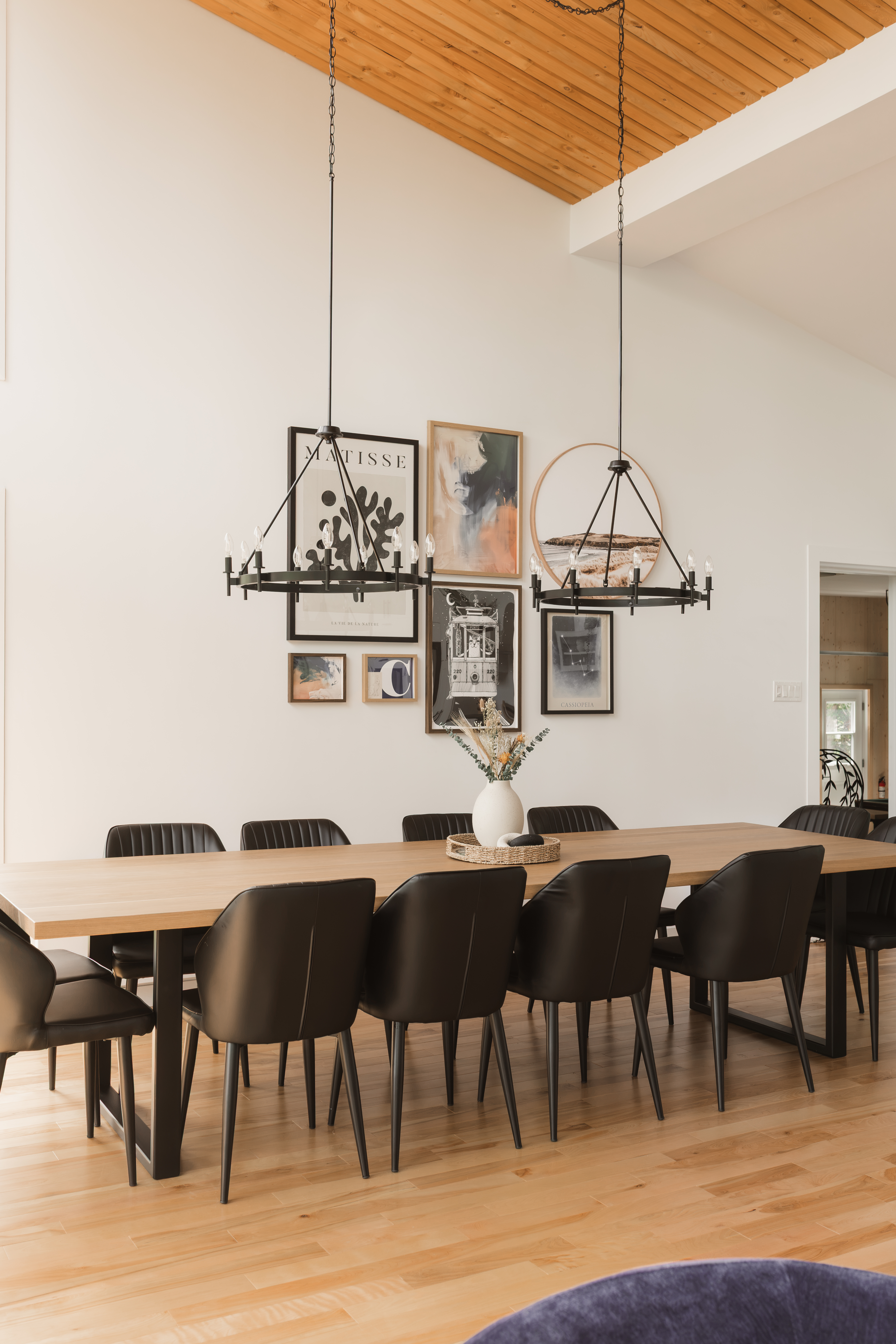 Grande table à manger sur mesure entourée de chaises noires sous un plafond cathédrale en bois | aménagement de chalet locatif pour 12 personnes | designer d'intérieur, Élévation Studio Design à Thetford Mines