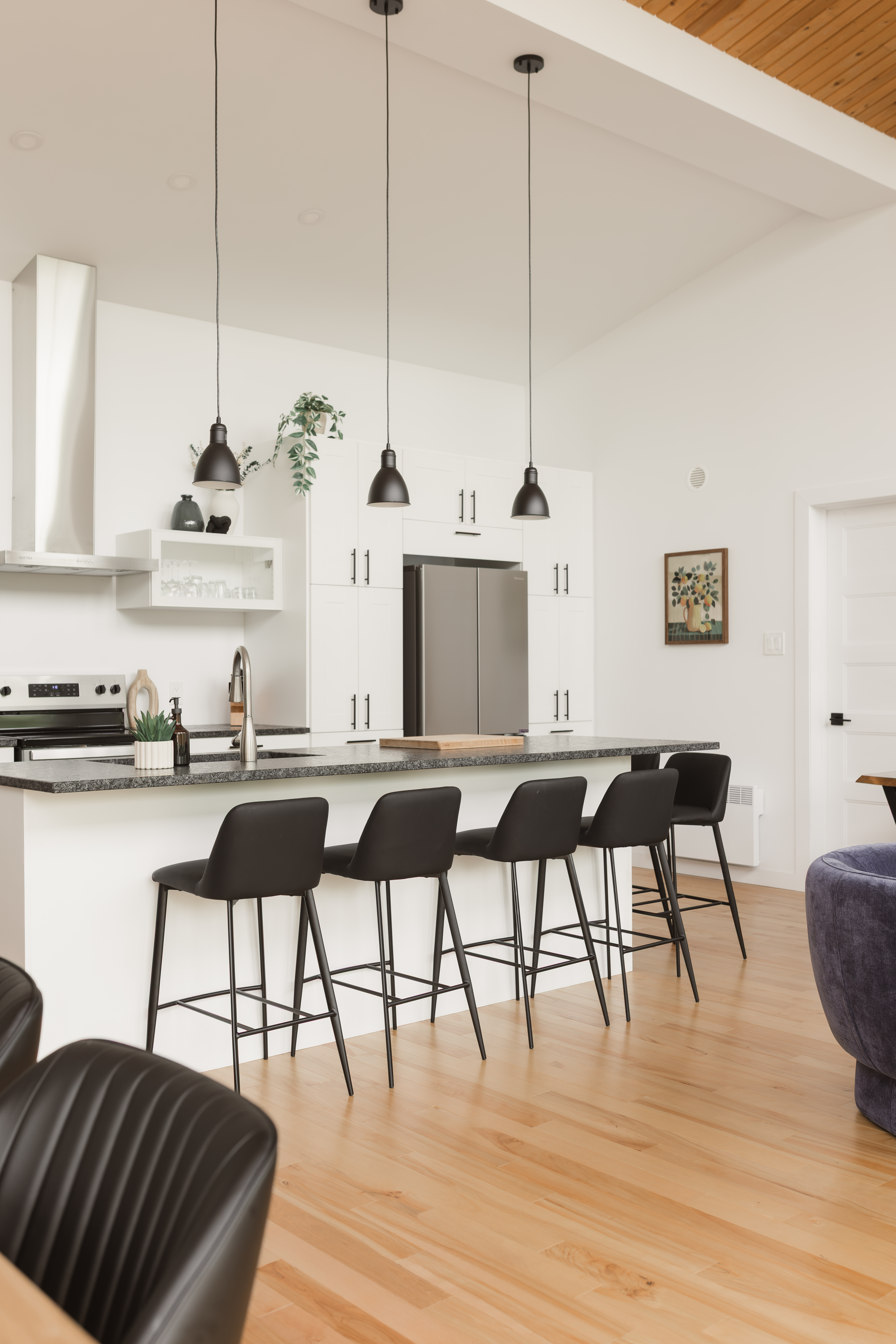 Grand îlot de cuisine avec tabourets noirs et suspensions dans un chalet à aire ouverte | cuisine de chalet locatif pour grand groupe | designer d'intérieur, Élévation Studio Design à Thetford Mines