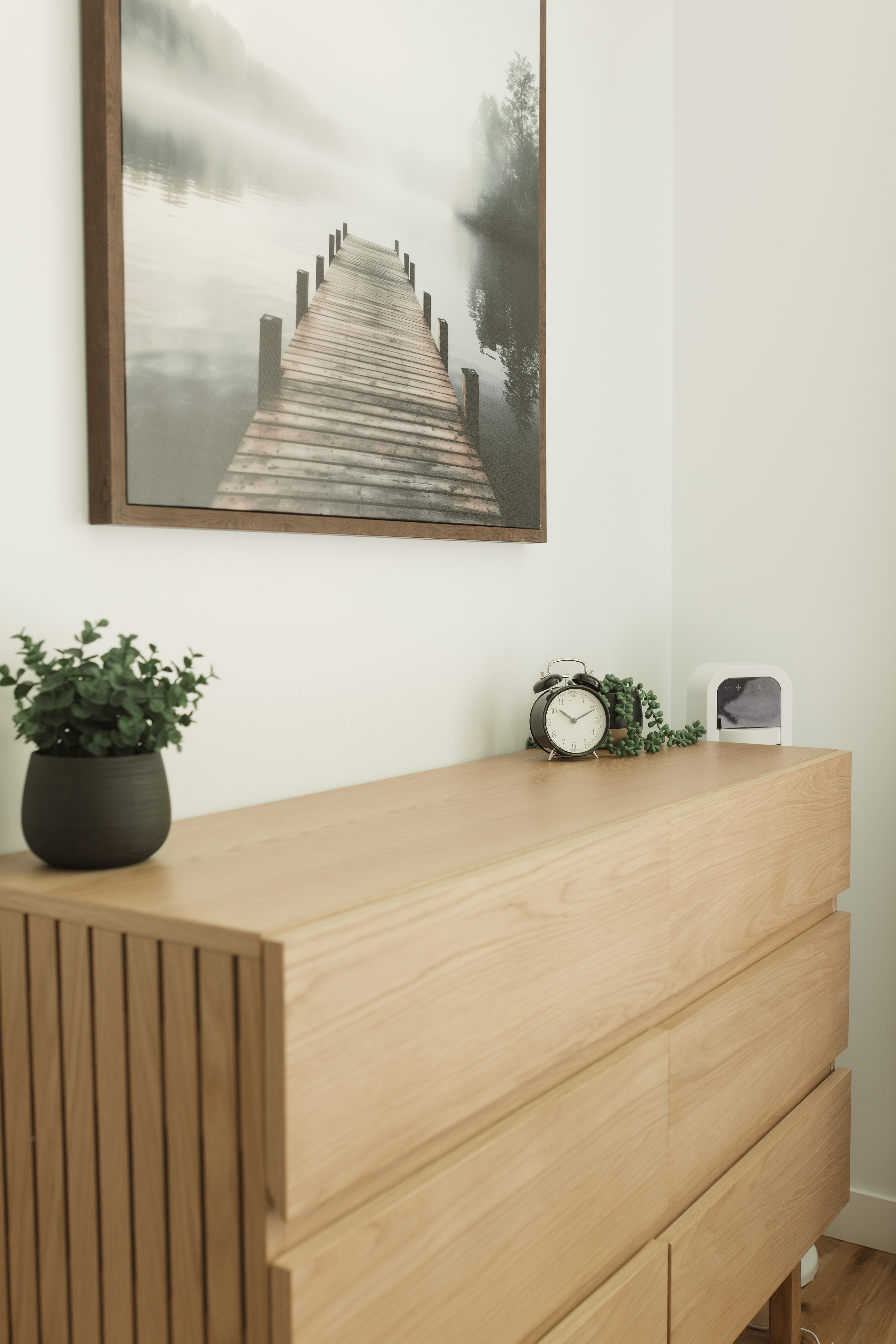 Une des quatre chambres du chalet locatif : commode en bois pâle qui maximise le rangement des locataires, avec quelques accessoires décoratifs chaleureux